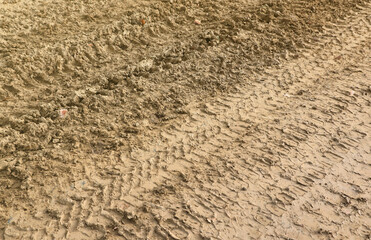 Wheel track on mud. Traces of a tractor or heavy off-road car on brown mud in a wet meadow