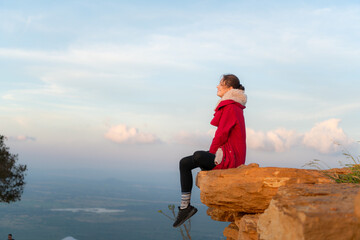 Portrait of a beautiful young woman in red coat on the background of blue sky