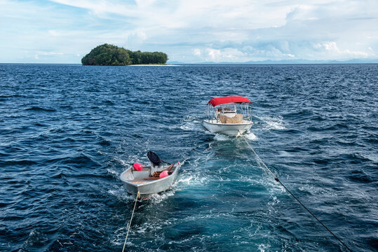 Two speedboats being towed behind a boat in the ocean, Raja Ampat, West Papua, Indonesia