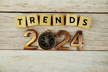 Trends of 2024 alphabet letters with magnifying glass on wooden background