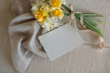 Overhead view of a bunch of daffodils with a blank card on a table