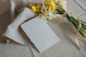 Overhead view of a bunch of daffodils with a blank card on a table