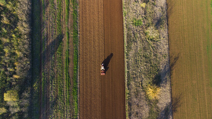 Aerial view of a tractor sowing wheat in a ploughed field, San Giuliano Nuovo, Alessandria, Piedmont, Italy