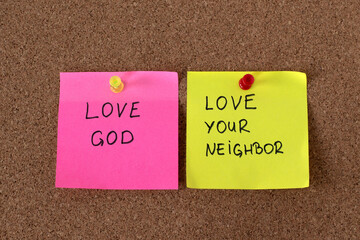 Love God, love your neighbor, handwritten notes on cork pinning board. Christian obedience and...