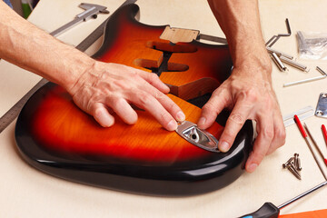 Guitar technician installs jack plate in guitar body.