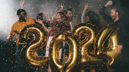 Group of happy people celebrating 2024 New Year while dancing and throwing confetti in night club