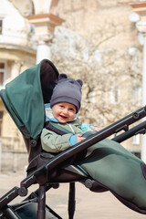 Smiling baby child in a stroller in the spring park