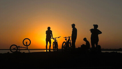Fototapeta na wymiar Silhouettes of the people on the beach with mountain bikes