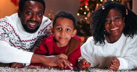 Close up of African American happy family with little boy tapping on tablet spending time together...
