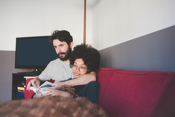 Young multiethnic couple relaxing lying couch under blanket