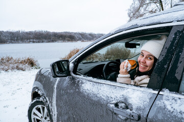 woman eat burger sitting in car at the frozen lake beach