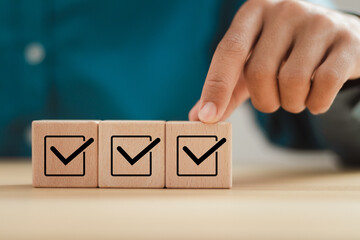 Checklist survey concept. Man hand putting wooden cube with checklist icon. Survey checklist, assessment, quality control.