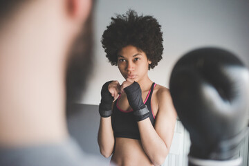 Young multiethnic woman at home training with coach doing boxe exercise
