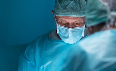 Team of medical doctors performs surgical operation in modern operating room using high-tech...