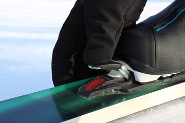 A skier in black sports touch gloves fixes a boot in a touring ski mount