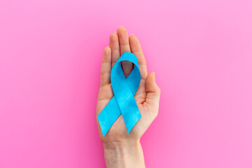 Blue ribbon symbol of colon or prostate cancer with hands. Medical support and prevention
