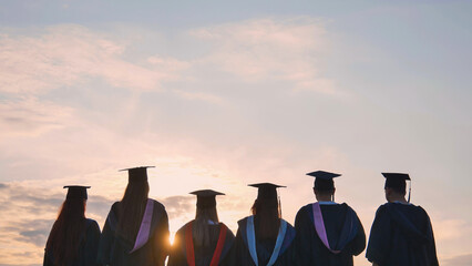 Silhouettes of graduating students at sunset.