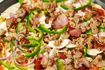 Raw St. Louis-Style Pizza homemade on a wooden background, with cheese, pepper, bacon onion