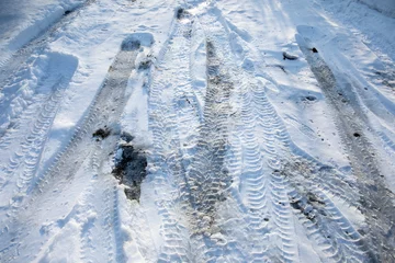 Poster Frozen winter snowy road with tire mark. Dangerous seasonal road conditions. Tire trail on ice. © SeNata