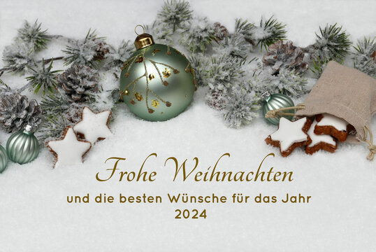 Weihnachtskarte: Winterliche Kulisse mit  Weihnachtskugeln, Tannenzweigen und Zimtsternen auf Schnee. Frohe Weihnachten und die besten Wünsche für das Jahr 2024.