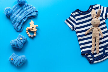 Set of baby boy dress - blue bodysuit with knitted hat and boots, top view. Kids clothing flat lay