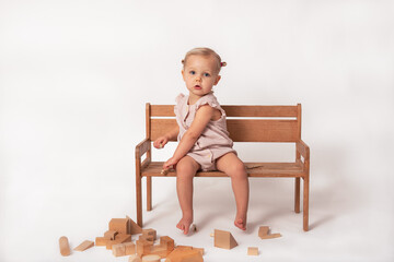 little girl sitting on a bench playing with wooden blocks