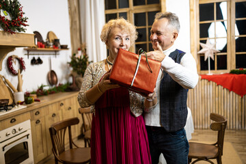 Christmas gift. Elderly man giving christmas gift to his smiling wife.