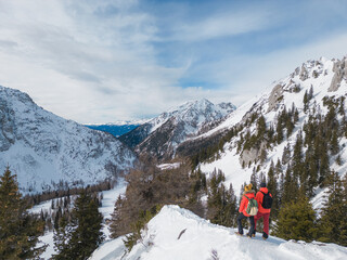 Mountaineer couple enjoy the amazing snowy landscape from the top of a mountain, aerial view
