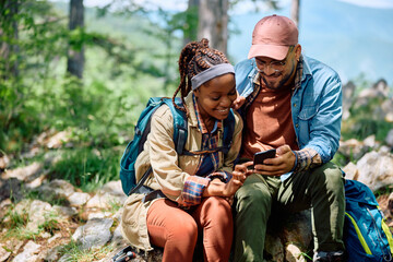 Happy couple of hikers using smart phone in mountains.