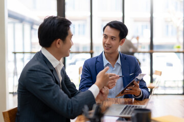 Asian businessman having a discussion with his colleague in an office. Asia two business man using a laptop in a meeting.