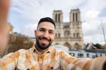 handsome man in france making selfie in paris at notre dame