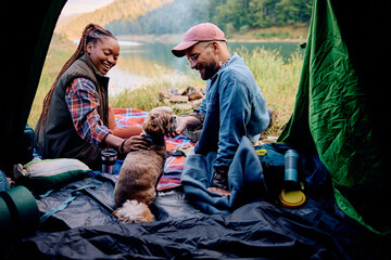 Happy couple of campers enjoying with their dog in nature.