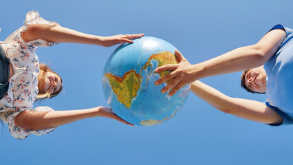 A girl and a guy swivels a globe of the world. The concept of peace and creation.