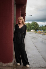 Portrait of a young beautiful blonde girl in dark clothes in an urban environment.