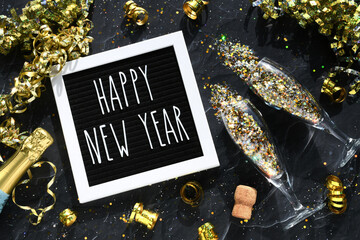 Welcoming the New Year - flat lay champagne glasses bottle gold glitter confetti golden streamers © MargJohnsonVA