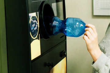 Reverse vending recycling machine that dispenses cash. Man hand puts plastic bottle to the machine
