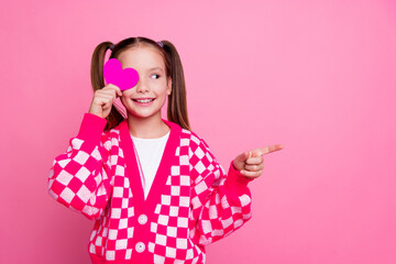 Portrait of cute girl with ponytails wear print sweater holding heart on eye look directing empty...