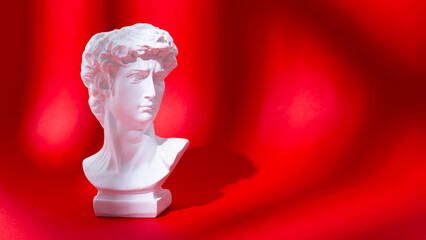 Web banner with an artificial statue of David on a red background. Creative modern greeting card...