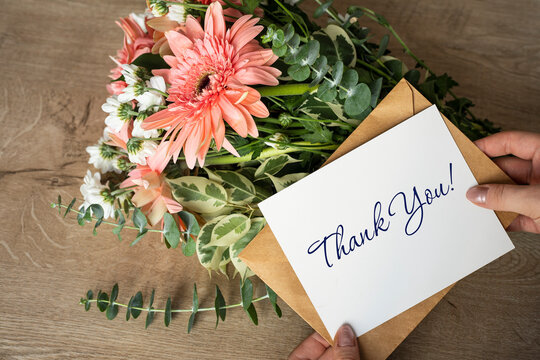 Thank you card in hands, message, envelope, flowers bouquet