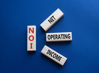 NOI - Net Operating Income symbol. Concept word NOI on wooden cubes. Beautiful deep blue background. Business and NOI concept. Copy space.
