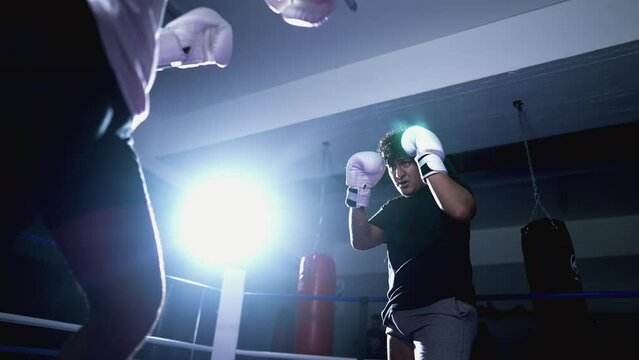 Muay Thai fighter defending himself from opponent's kicks and blows inside boxing ring