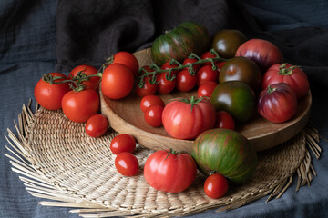 different varieties of tomato on a straw and wooden plate