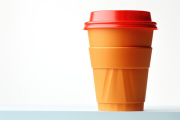 A plastic cup with a red lid sitting on a table. Suitable for any beverage-related themes or everyday objects.