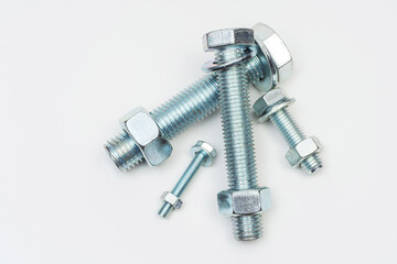 group of bolts and nuts on a white background. bolts, washers and nuts assembled on a light background. photo of fasteners with threads for the catalog