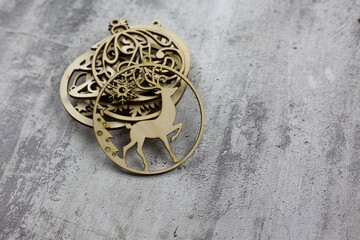 Flat wooden toy in the shape of a deer with antlers in a circle lies on a stack of New Year's toys on a white background