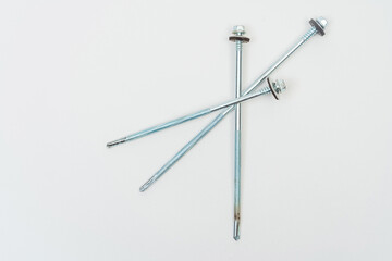 long screws on a white background. self-tapping screws with a tip for metal and concrete on a light...