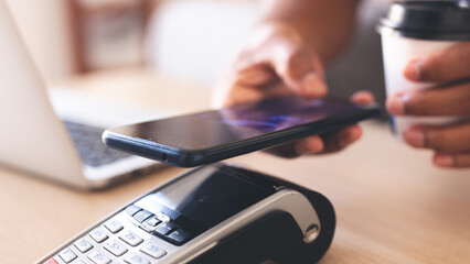 Hands using digital wallet app on mobile device to make contactless payment, emphasizing...