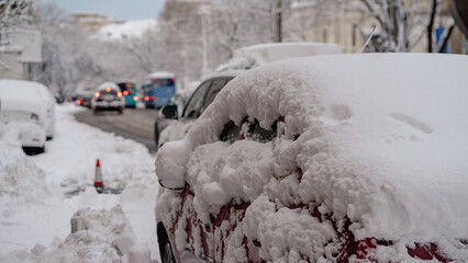 Cars covered with snow from the first snow fall of the year. Winter concept, snowy cars parked on the street, deep layer of snow