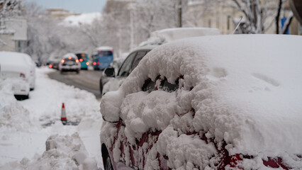 Cars covered with snow from the first snow fall of the year. Winter concept, snowy cars parked on...