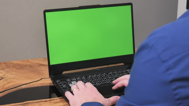 Side View Of A Man Behind A Laptop. Over Shoulder View Of White Male Businessman And Laptop With Green Screen